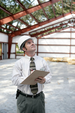 A man with a clipboard overseeing new roof installation