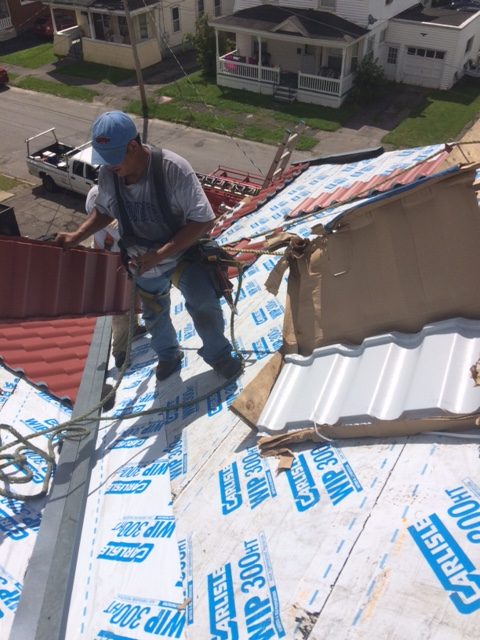 A man installing metal shingles on a roof