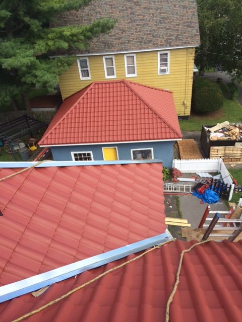 A roof with new red metal shingles