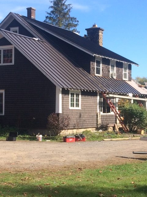 A brown house with a new metal roof being installed
