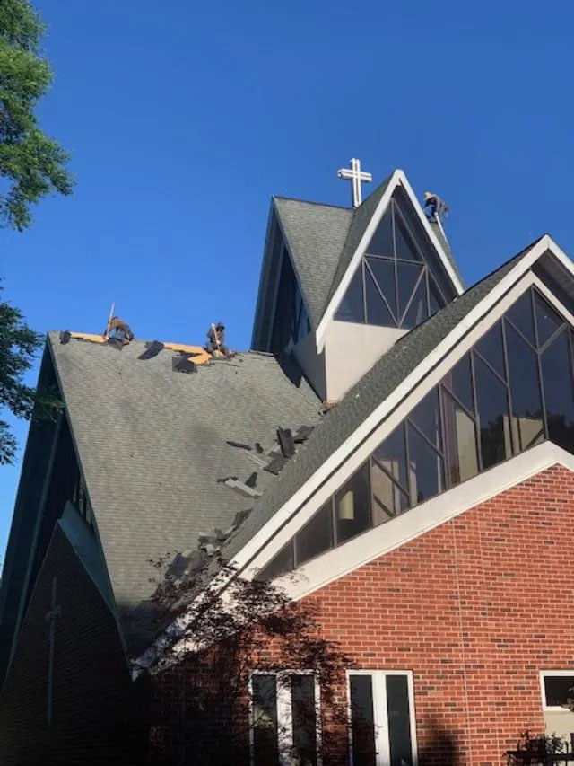 Two men on the roof of a church, replacing it's shingles