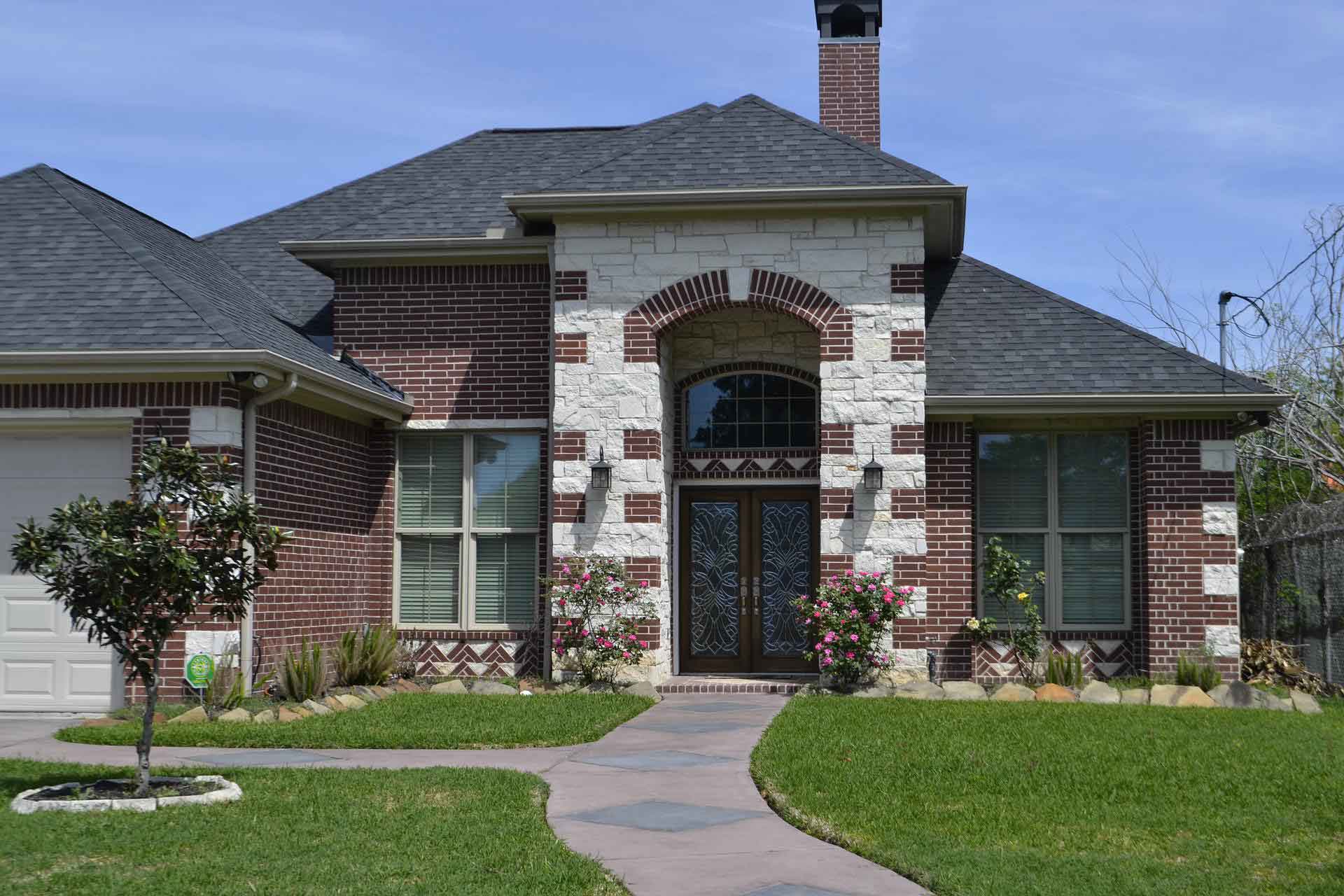 A brick house with a grey shingled roof